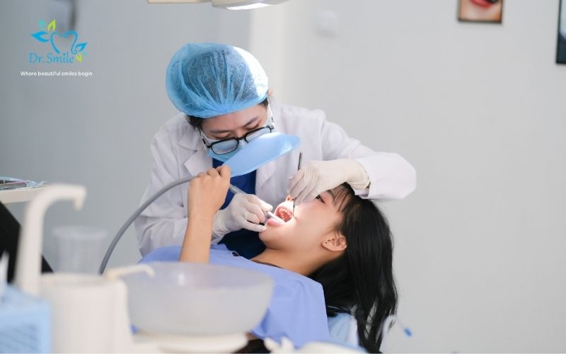 A dentist in a lab coat and hairnet performing a dental procedure on a patient